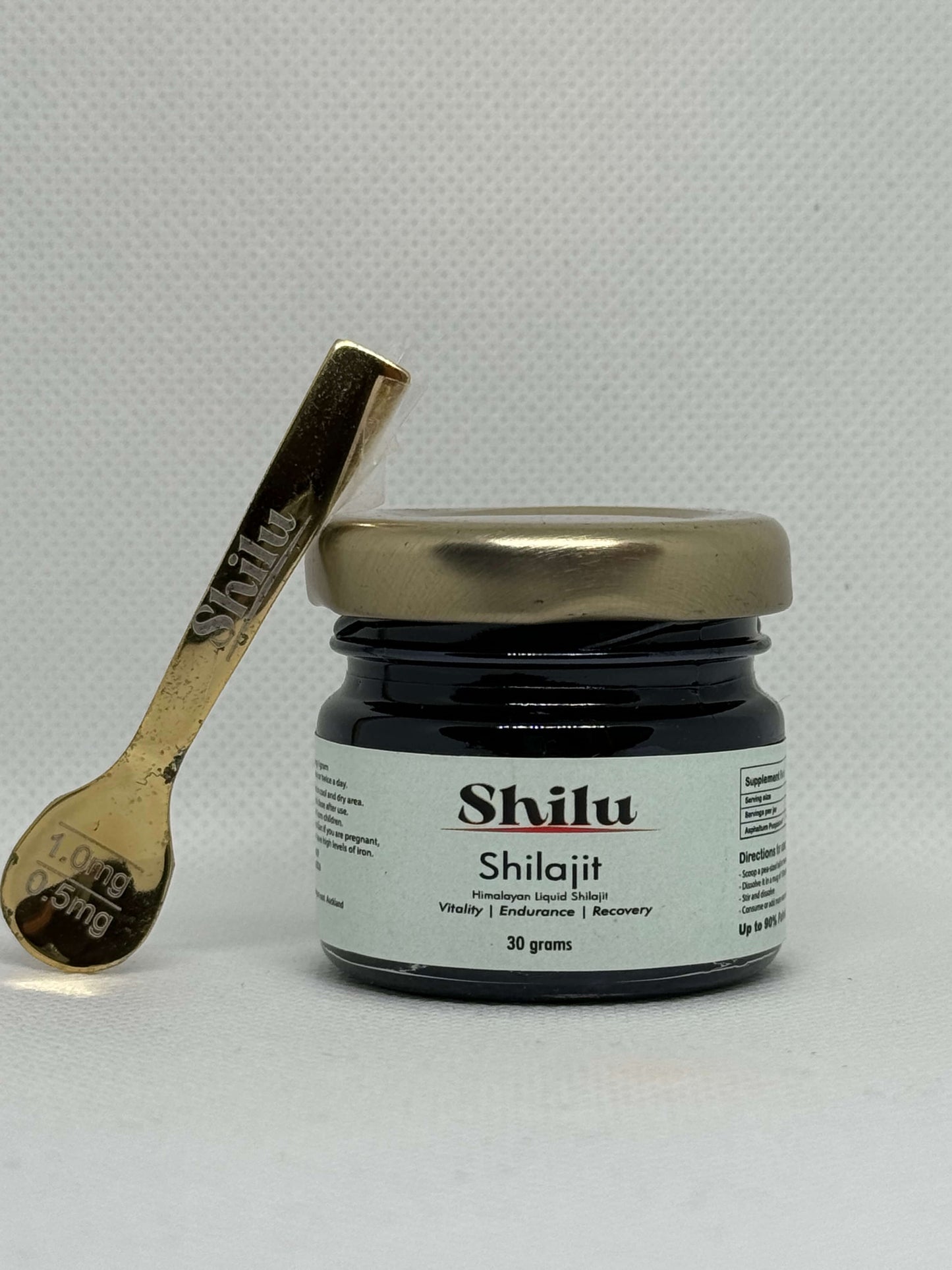 Jar of Shilu Shilajit nz with a gold spoon on a light gray background